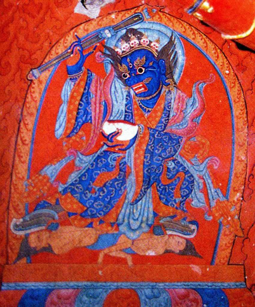 Tibet Guge 06 Tsaparang White Temple 03 01 Mahakala Below Hayagriva�s outstretched right arm is a beautiful painting of blue Mahakala, a wrathful Tantric deity and manifestation of Avalokiteshvara (Tib. Chenrezig). He is blue with fanged teeth and a tiara of skulls, wears richly decorated robes, holds a staff in his right hand and a skull cup brimming with blood in his left. Photo - Weyer/Aschoff: Tsaparang, Tibets Grosses Geheimnis.